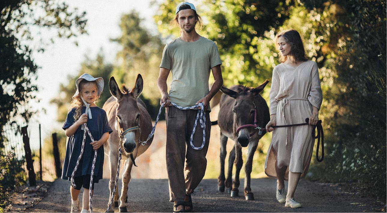Familie wandert mit Eseln auf einem sonnigen Weg in Montenegro